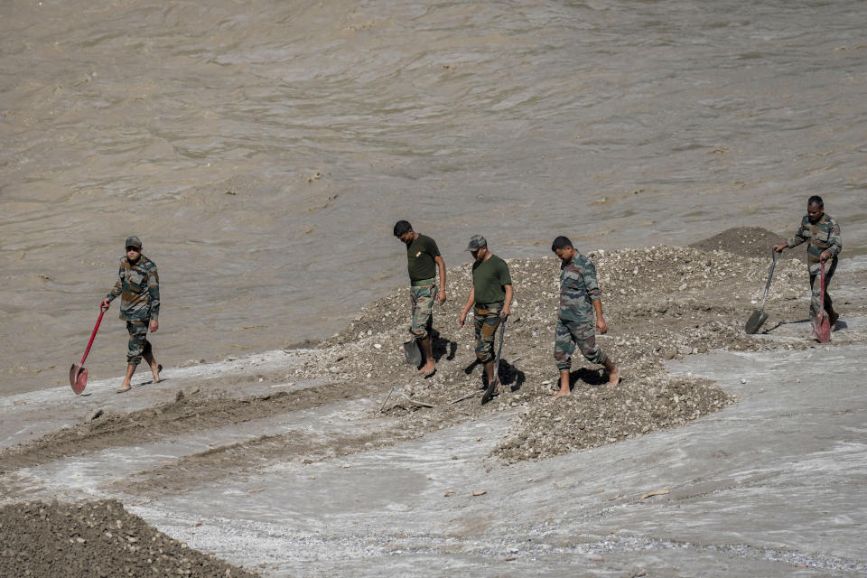 Indian army personnel walk along the Teesta river digging as they continue the search for those missing in Bardang, east Sikkim, India, Sunday, Oct. 8. 2023. Rescuers continued to dig through slushy debris and ice-cold water in a hunt for survivors after a glacial lake burst through a dam in India’s Himalayan northeast, shortly after midnight Wednesday, washing away houses and bridges and forcing thousands to flee. (AP Photo/Anupam Nath)