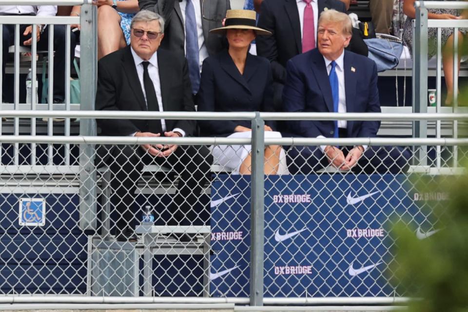 Donald Trump and Melania Trump in a hat sitting in a stand with her father.