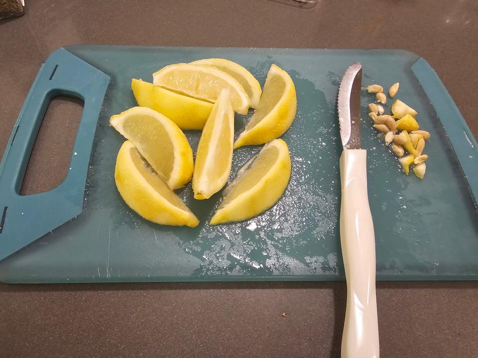 Lemon slices on cutting board alongside knife and seeds
