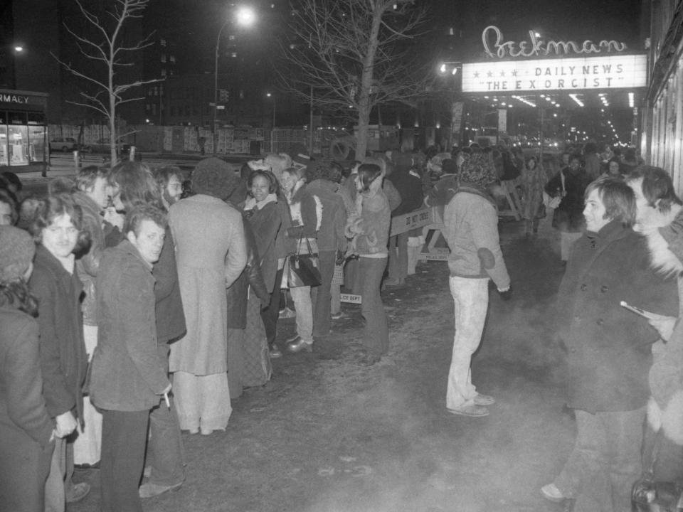 Crowds of people lining up to see "The Exorcist" outside a movie theater.