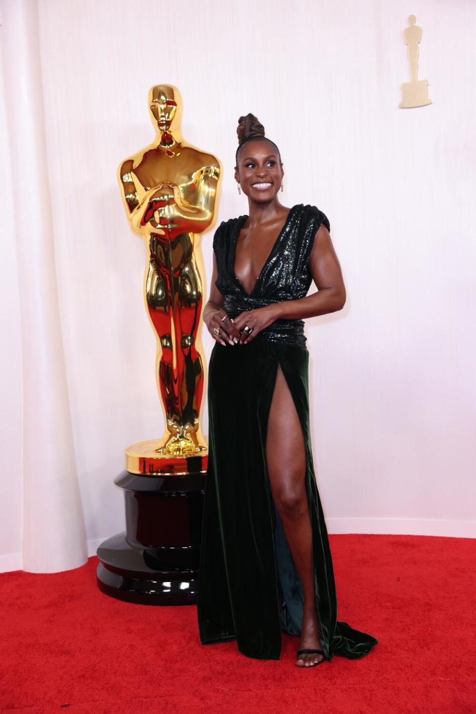 Issa Rae wears a sequined deep green gown with a plunging neckline.