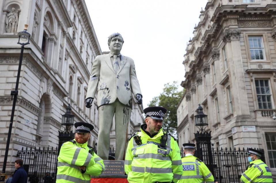 Police officers stand next to a statue stained with oil (REUTERS)