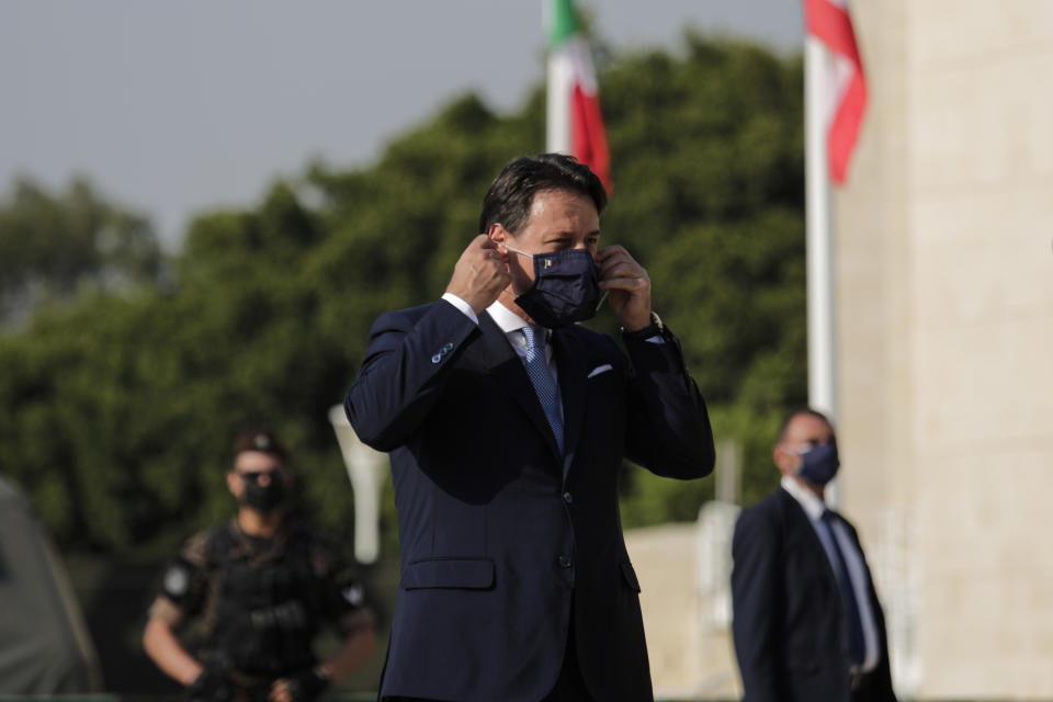 Italian Prime Minister Giuseppe Conte fixes his face mask before addressing Italian soldiers during a visit to an Italian field hospital set up at the Lebanese University in the Hadath district of Beirut, Lebanon, Tuesday, Sept. 8, 2020. Conte said Tuesday his country will support Lebanon's economic and social growth, expressing hopes that a new government is formed quickly — one that would start the reconstruction process in the wake of last month's Beirut explosion and implement badly needed reforms. (AP Photo/Hassan Ammar)
