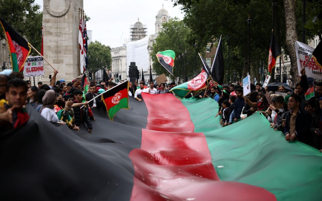 A group of demonstrators carry a large Afghanistan national flag as they walk through central London - Henry Nicholls/Reuters