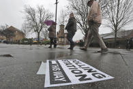 A polling station signpost lies on the pavement as voters approach a polling station in Twickenham, England, Thursday, Dec. 12, 2019. British voters are deciding who they want to resolve the Brexit conundrum in an election seen as one of the most important since the end of World War II. (AP Photo/Frank Augstein)
