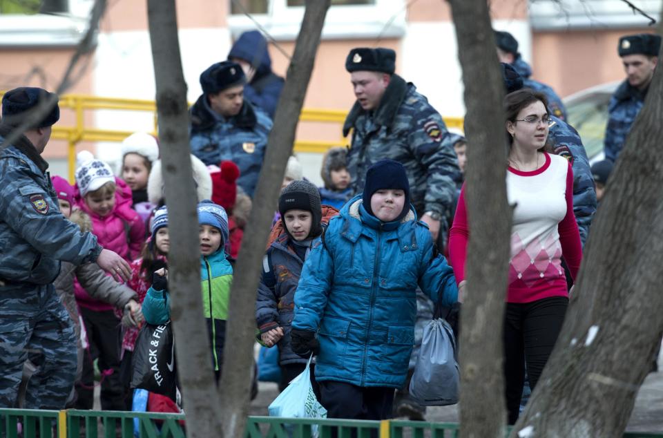 Police officers evacuate children from a Moscow school on Monday, Feb. 3, 2014. An armed teenager burst into his Moscow school on Monday and killed a teacher and policeman before being taken into custody, investigators said. None of the children who were in School No. 263 were hurt, said Karina Sabitova, a police spokeswoman at the scene. The student also wounded a second police officer who had responded to an alarm from the school, she said. (AP Photo/Alexander Zemlianichenko)