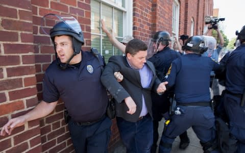 Police escort Jason Kessler, organizer of the 'Unite the Right' rally, as he is rushed away after a press conference at City Hall in Charlottesville, Virginia - Credit: EPA