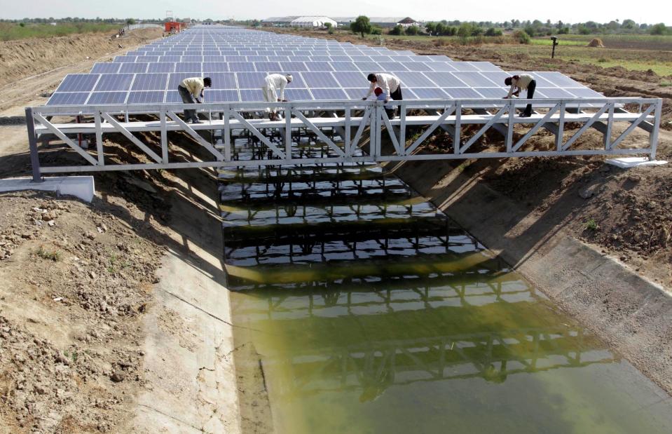 Indian workers give finishing touches to installed solar panels covering the Narmada canal at Chandrasan village, outside Ahmadabad, India, on April 22, 2012.