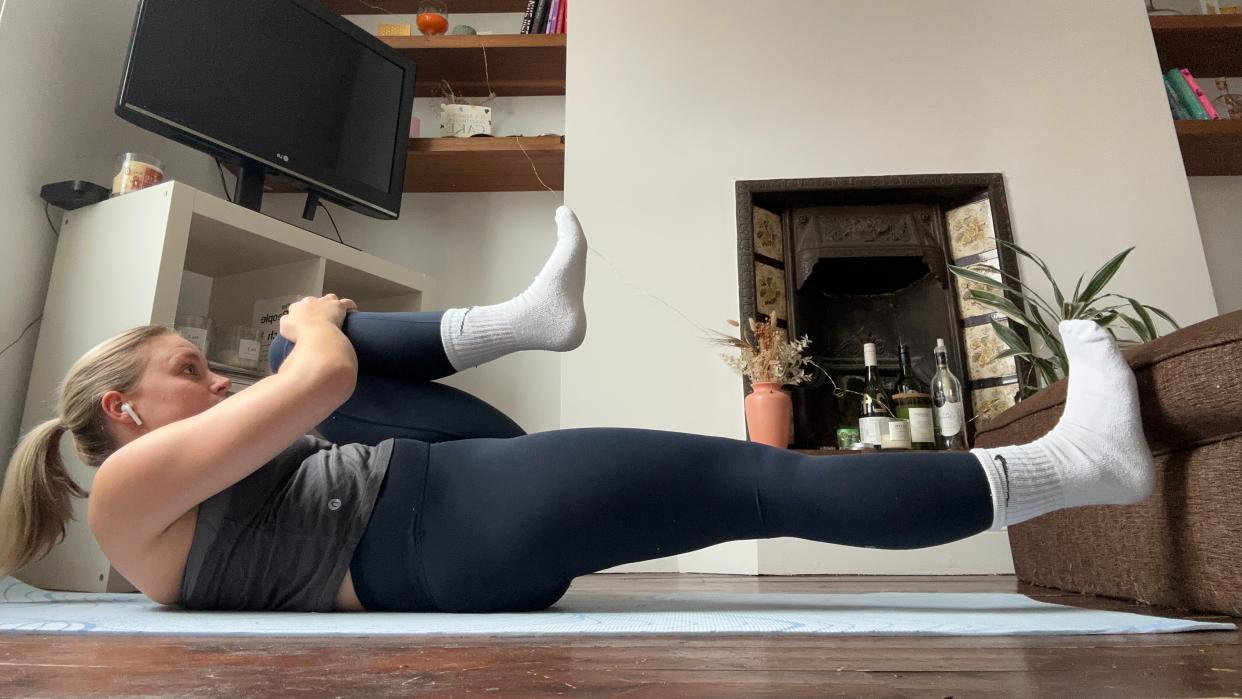  Fitness writer Alice Porter wearing workout gear performing yoga routine in her living room. 