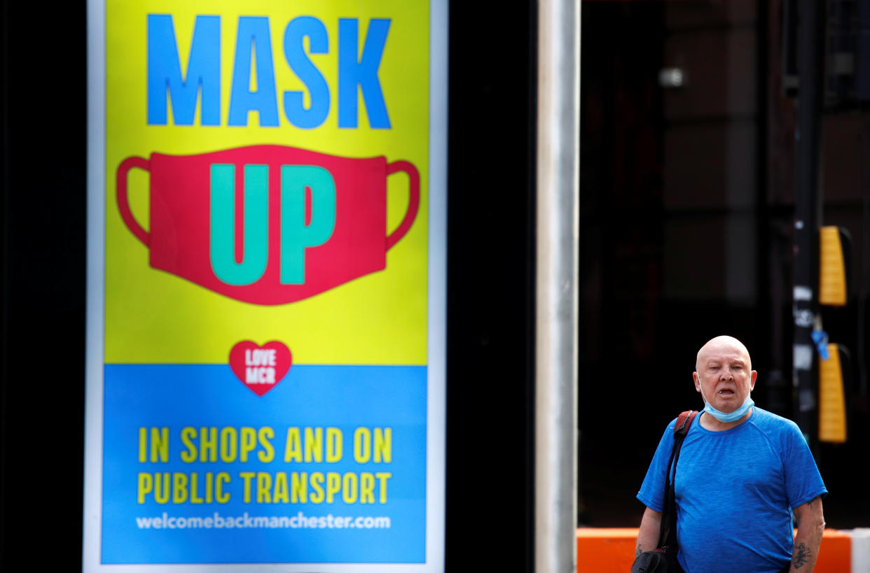 A man stands next to a sign promoting the use of protective face mask in Manchester, as the city and surrounding areas face local restrictions in an effort to avoid a local lockdown being forced upon the region, amid the coronavirus disease (COVID-19) outbreak, in Manchester, Britain August 3, 2020. REUTERS/Phil Noble