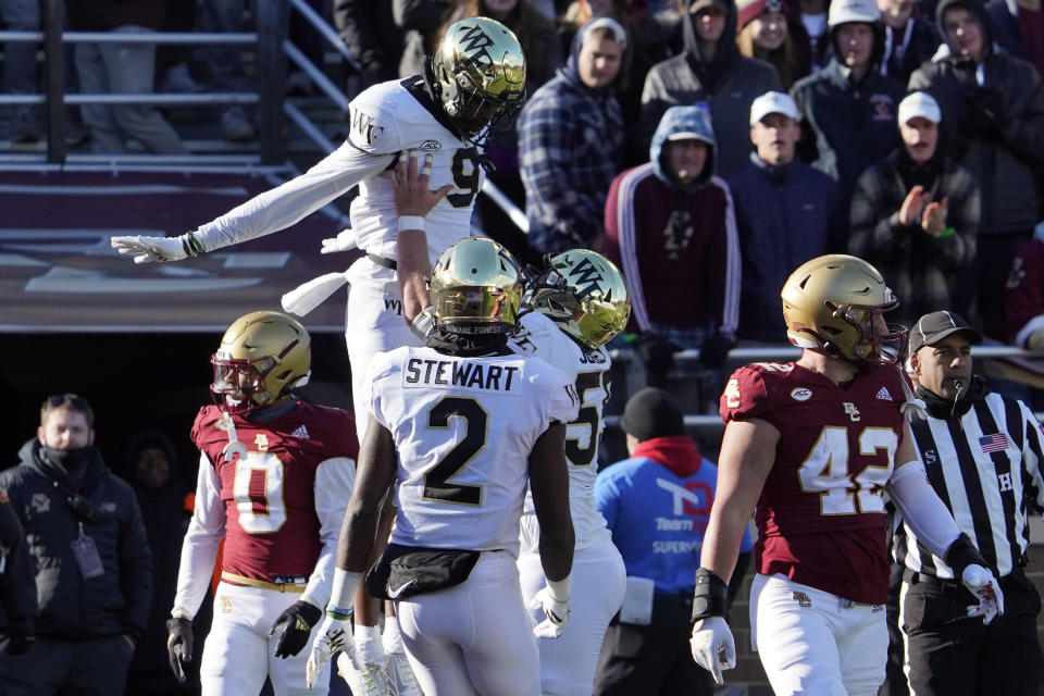 Wake Forest wide receiver A.T. Perry (9) is lifted by teammate Michael Jurgens (55) after scoring a touchdown as Boston College linebacker Vinny DePalma (42) looks away in the first half of an NCAA college football game, Saturday, Nov. 27, 2021, in Boston. (AP Photo/Mary Schwalm)