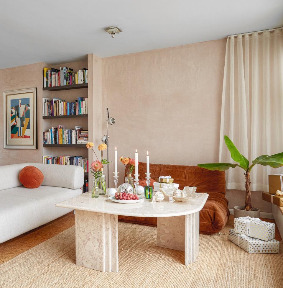 A living room in neutral tones, with a cream curtain half hung on the wall