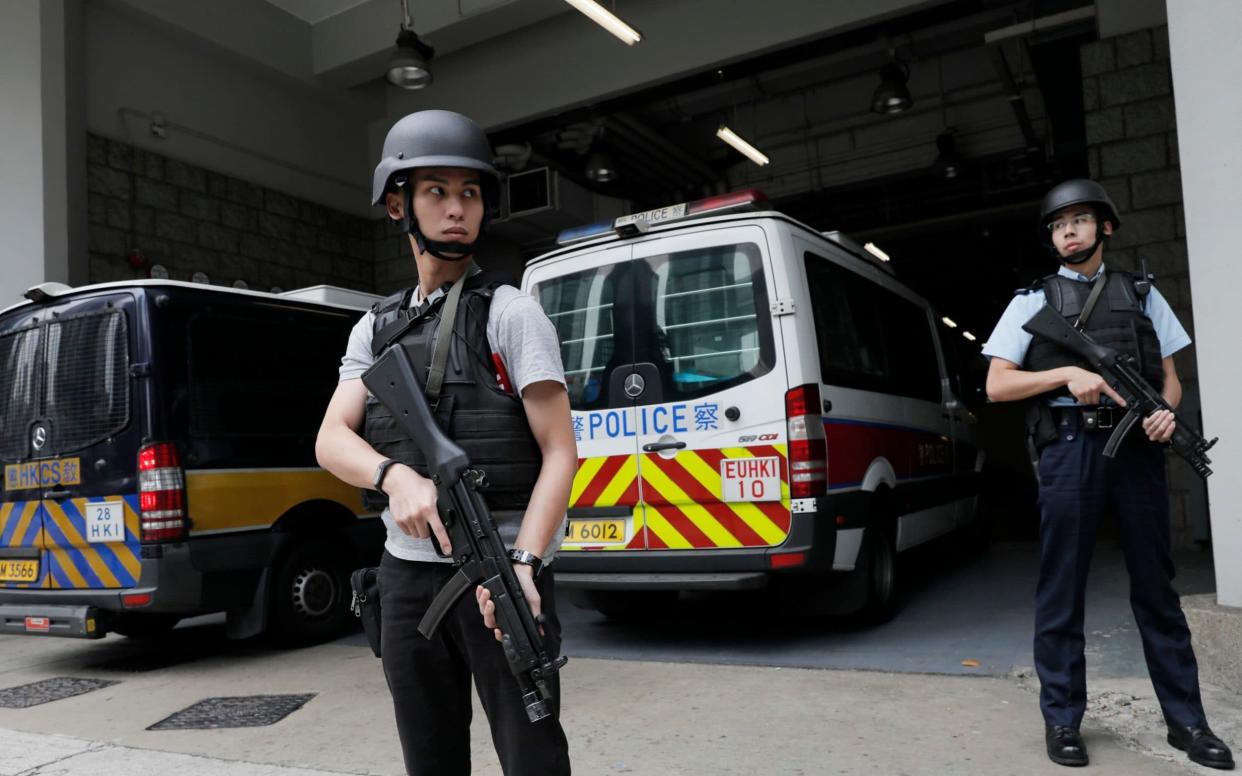 Police officers stand guard next to prison bus which carries British banker Rurik Jutting - AP