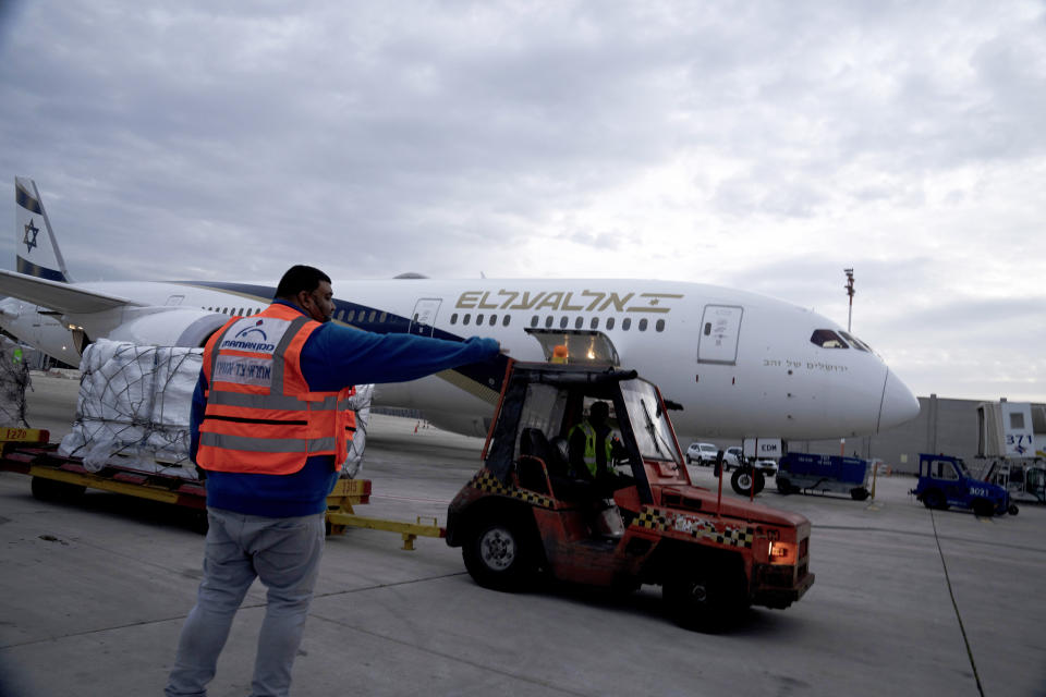 Ground crew move pallets of a shipment of Pfizer's antiviral COVID-19 pill, Paxlovid, on arrival at Ben Gurion International airport near Tel Aviv, Thursday, Dec. 30, 2021. (AP Photo/Maya Alleruzzo)