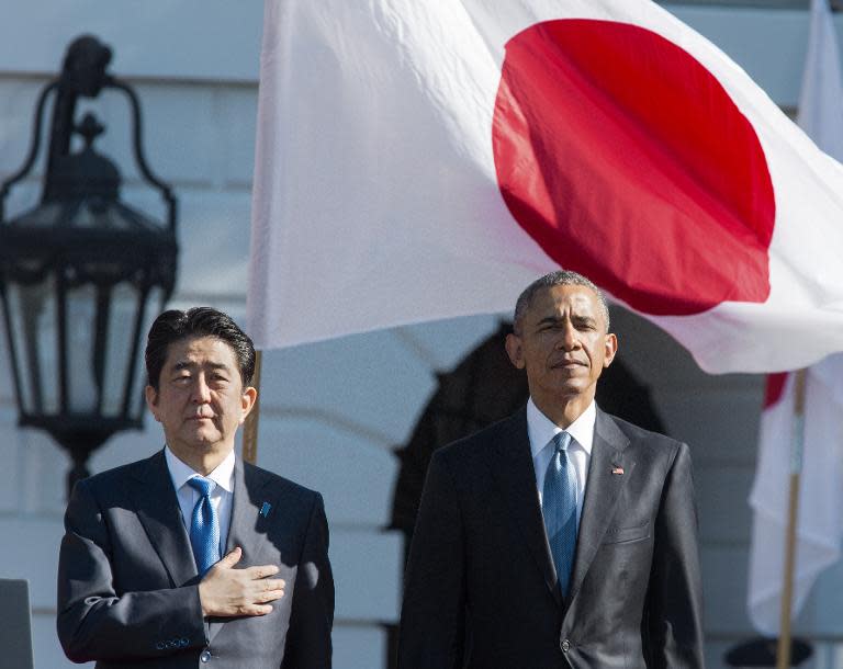 Barack Obama and Shinzo Abe listen to their national anthems during arrival ceremonies at the White House on April 28, 2015, in Washington, DC