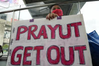 An anti-government protester holds a sign in Bangkok, Thailand, Friday, Sept. 30, 2022. Thailand’s Constitutional Court ruled Friday that Prime Minister Prayuth Chan-ocha can remain in his job and did not violate a constitutional provision limiting him to eight years in office. (AP Photo/Sakchai Lalit)