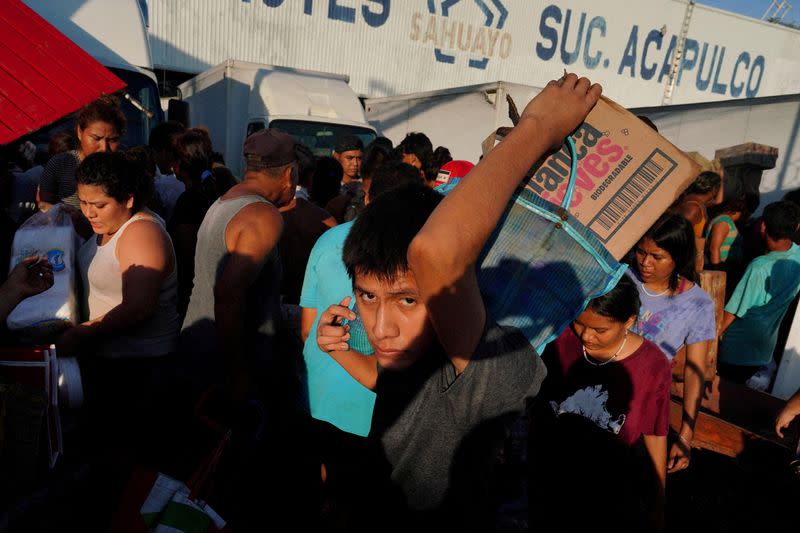 La gente sale con productos de un supermercado que fue asaltado tras el huracán Otis, en las afueras de Acapulco, México