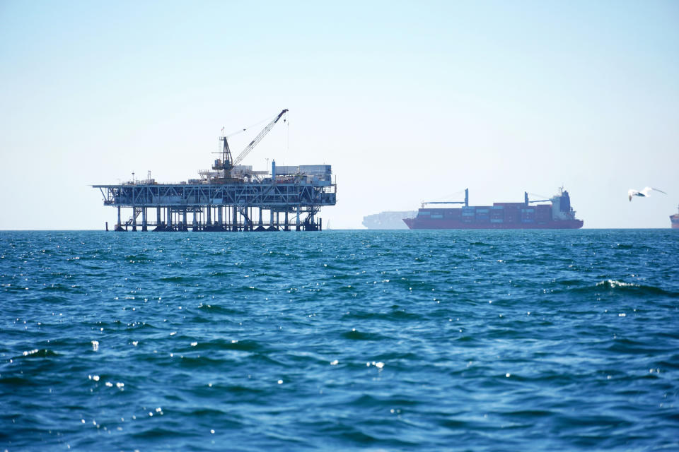 Dozens of cargo vessels are seen anchored offshore, sharing space with about a half dozen oil platforms, before heading into the Los Angeles-Long Beach port, Tuesday, Oct. 5, 2021. (AP Photo/Eugene Garcia)