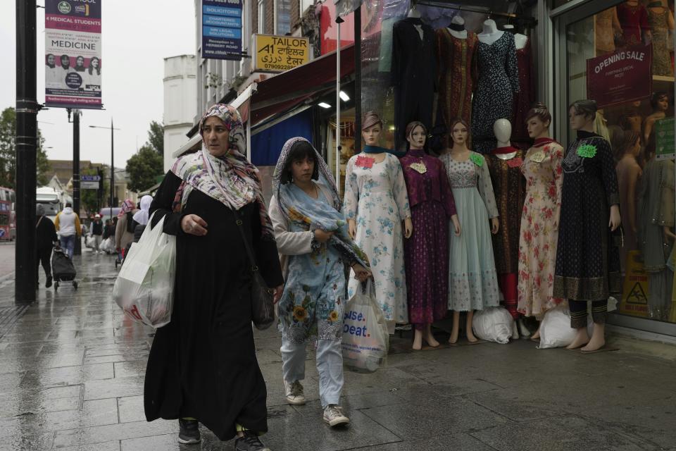 People walk alone a street in the district of Southall in London, Tuesday, Sept. 13, 2022. In a church in a West London district known locally as Little India, a book of condolence for Queen Elizabeth II lies open. Five days after the monarch’s passing, few have signed their names. The congregation of 300 is made up largely of the South Asian diaspora, like the majority of the estimated 70,000 people living in the district of Southall, a community tucked away in London's outer reaches of London and built on waves of migration that span 100 years. (AP Photo/Kin Cheung)