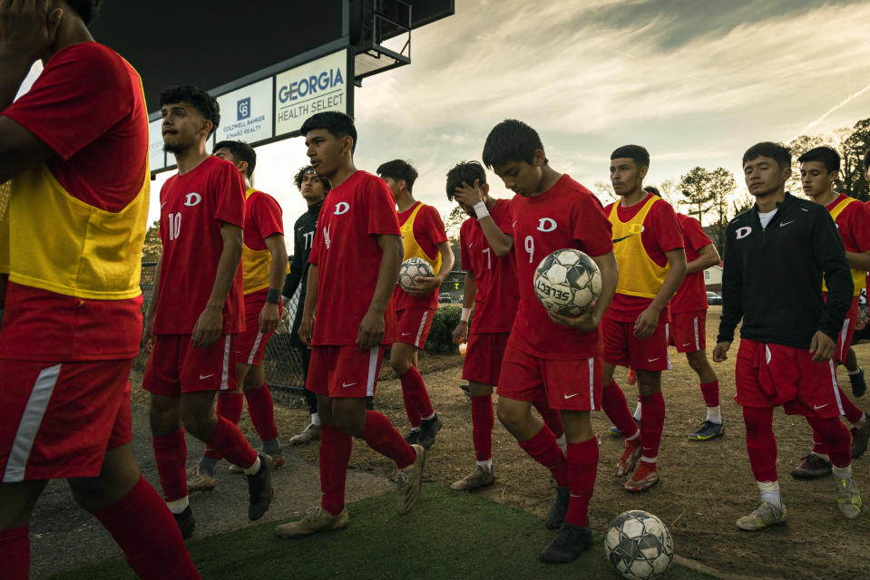 El equipo varonil del bachillerato Dalton High School compuesto por generaciones de inmigrantes salta al campo de juego para disputar el clásico, como la gente local llama al enfrentamiento anual con Southeast Whitfield High School, en Dalton, Georgia, el 17 de marzo de 2022. (Audra Melton/The New York Times)