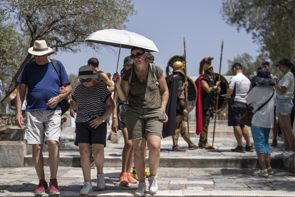 Tourists exit the ancient Acropolis of Athens as the Greek culture ministry shut down the monument most of the day because of heat, Friday, July 14, 2023. Temperatures were starting to creep up in Greece, where a heatwave was forecast to reach up to 44 degrees Celsius in some parts of the country over the weekend. (AP Photo/Petros Giannakouris)