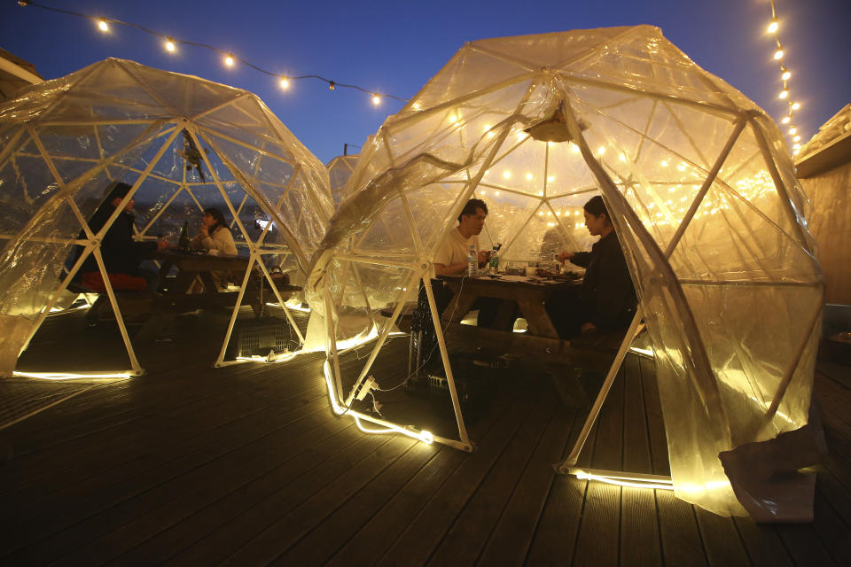 People enjoy outdoor dining at plastic bubbles, observing social distancing against the spread of the coronavirus at a restaurant near the Han River in Seoul, South Korea, Friday, April 9, 2021. (AP Photo/Ahn Young-joon)