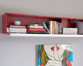 Hang a floating shelf cabinet above your bed so your books, DVDs and CDs are concealed behind a drop-down door. Line up the top of the unit with the top of your wall shelves or lower, if you prefer.