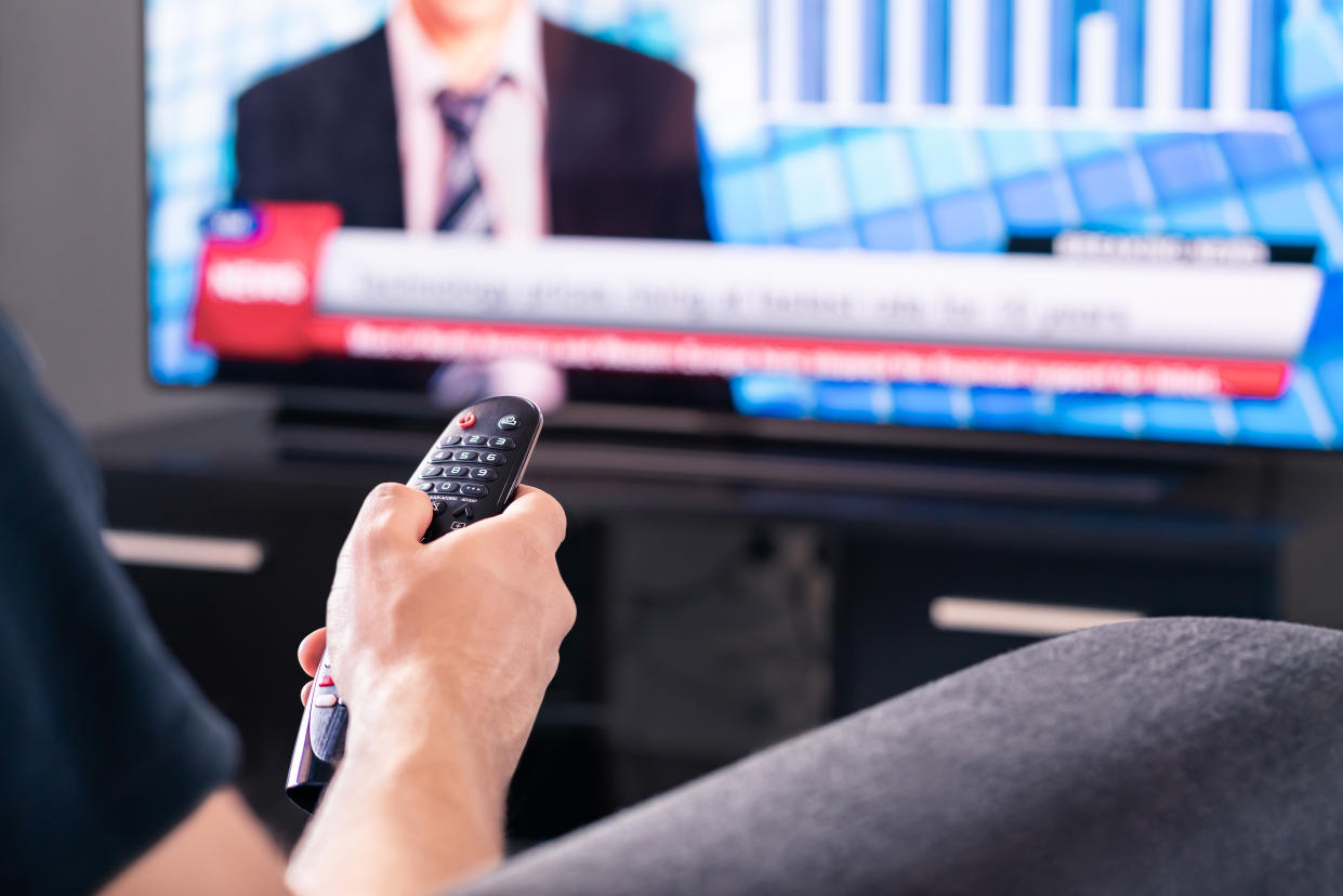 A man watches live television broadcast program. 