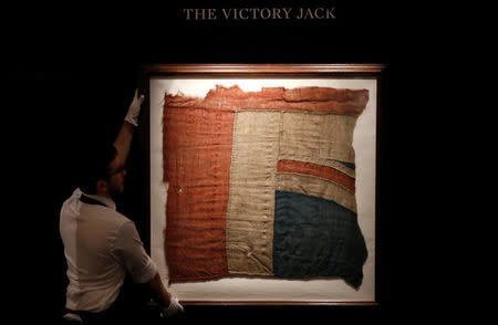 FILE PHOTO: A member of Sotheby's staff poses for a photograph with a large fragment of Lord Nelson's union flag which flew from the HMS Victory during the Battle of Trafalgar London, Britain January 11, 2018. REUTERS/Peter Nicholls/File Photo