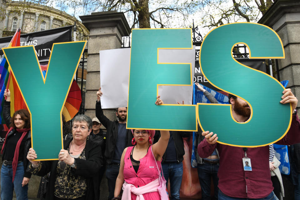 'Yes' vote campaigners cover anti-abortion group's graphic images related to pregnancy and abortion, with Irish and rainbow flags, and white billboards, outside Leinster House, the Irish Parliament, on Friday, May 4, 2018, in Dublin, Ireland.