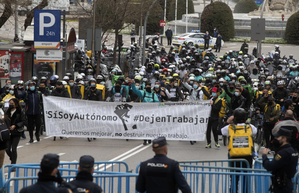 Delivery riders arrive to protest outside the Spanish parliament in Madrid, Wednesday March 3, 2021. Food delivery workers have staged protests across Spain, urging the government to approve a promised law granting them the right to choose between being company staff or self-employed. Media reports said more than 2,000 delivery riders gathered to protest in at least 10 Spanish cities on Wednesday. TBanner reads in Spanish ' Yes, I am an autonomous worker. Let us work. We want to work better, not destroy our work'. (AP Photo/Paul White)