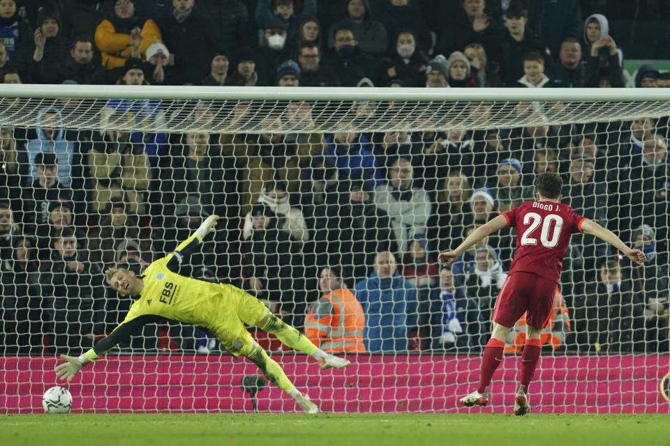 Liverpool's Diogo Jota, right, scores the winning penalty past Leicester's goalkeeper Kasper Schmeichel of the penalty shootout of the English League Cup quarter-final soccer match between Liverpool and Leicester City, at Anfield Stadium, in Liverpool, England, Wednesday Dec. 22, 2021. (AP Photo/Jon Super)