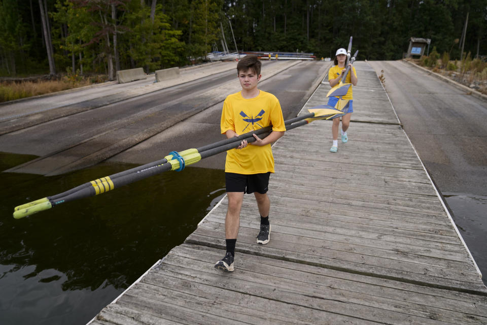 Callum Bradford, left, carries paddles to the boat ramp in preparation of his club team's rowing practice at Jordan Lake, Friday, Oct. 6, 2023, in Apex, N.C. Bradford, a transgender teen from Chapel Hill needed mental health care after overdosing on prescription drugs. He was about to be transferred to another hospital due to a significant bed shortage. A North Carolina hospital network is referring transgender psychiatric patients to treatment facilities that do not align with their gender identities. Though UNC Hospitals policy discourages the practice, administrators say a massive bed shortage is forcing them to make tough decisions. (AP Photo/Erik Verduzco)