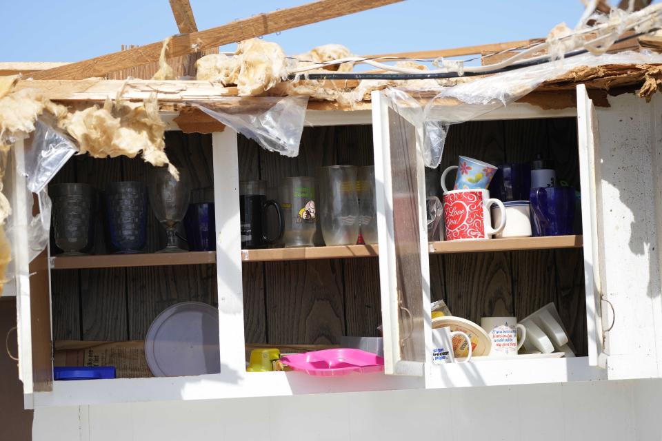 Glasses and mugs remain in a cupboard on Tuesday, March 28, 2023, even after a Silver City, Miss., home lost its ceiling and roof during a deadly Friday night tornado that hit a number of Mississippi communities. (AP Photo/Rogelio V. Solis)
