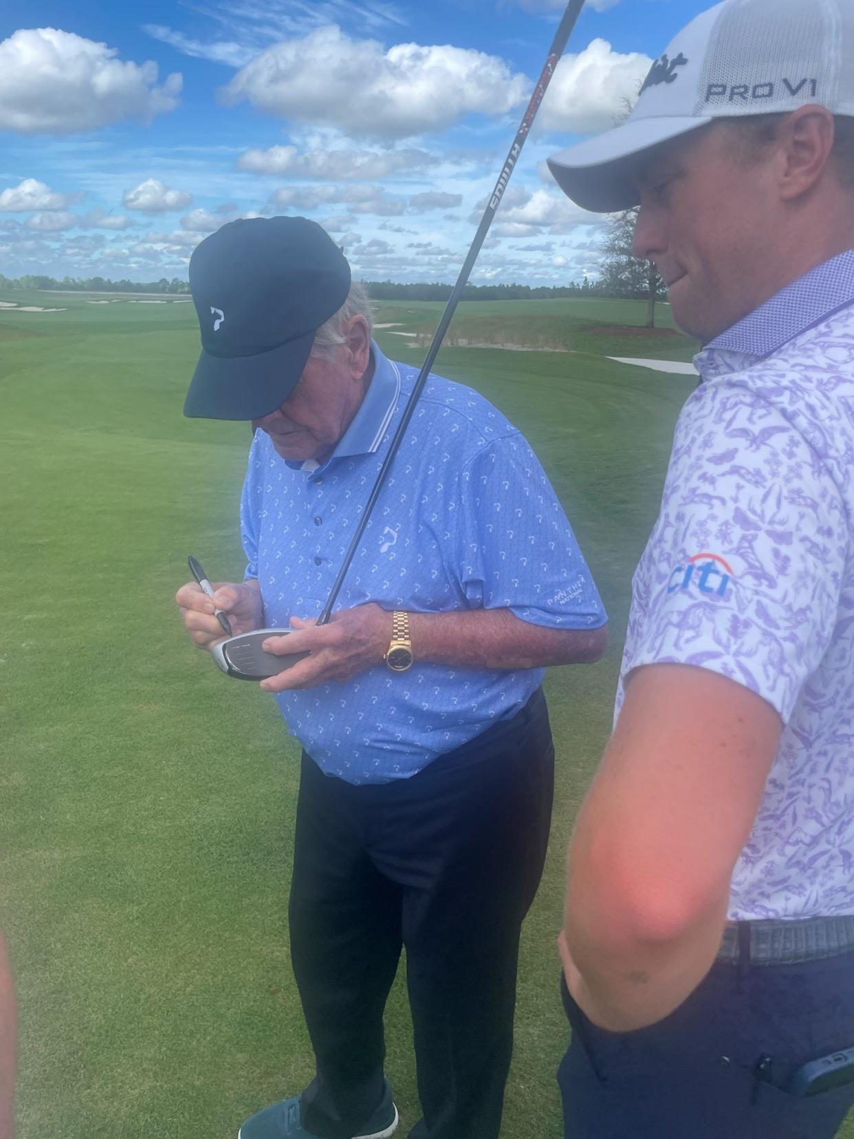 Jack Nicklaus signs the driver he used on Friday to hit a tee shot at the opening of Panther National