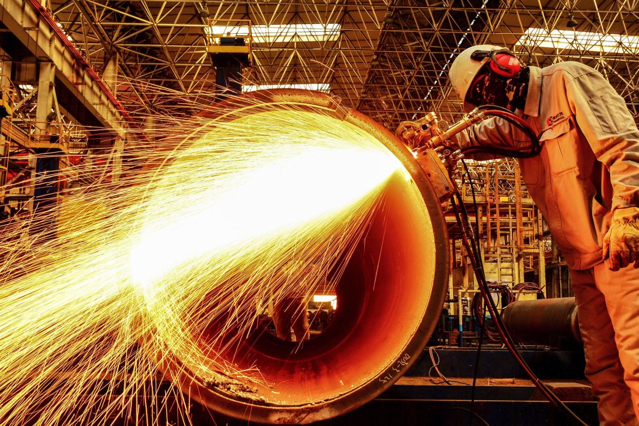 A worker cuts an oil pipe at a factory in Qingdao in China's eastern Shandong province on February 28, 2019. 