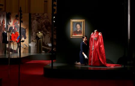 A member of the Royal Collection Trust poses for photographers next to Britain's Queen Elizabeth's 'Mantle of The Order of The British Empire' robe, ahead of the opening of an exhibition entitled 'Fashioning a Reign: 90 Years of Style from the Queen's Wardrobe', at Buckingham Palace, in London, Britain July 21, 2016. REUTERS/Peter Nicholls