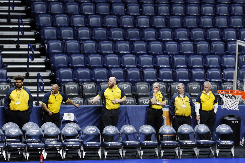 Security guards stand behind a team bench area at Bridgestone Arena after the NCAA college basketball games at the Southeastern Conference men's tournament were cancelled, Thursday, March 12, 2020, in Nashville, Tenn. The tournament was cancelled due to coronavirus concerns. (AP Photo/Mark Humphrey)