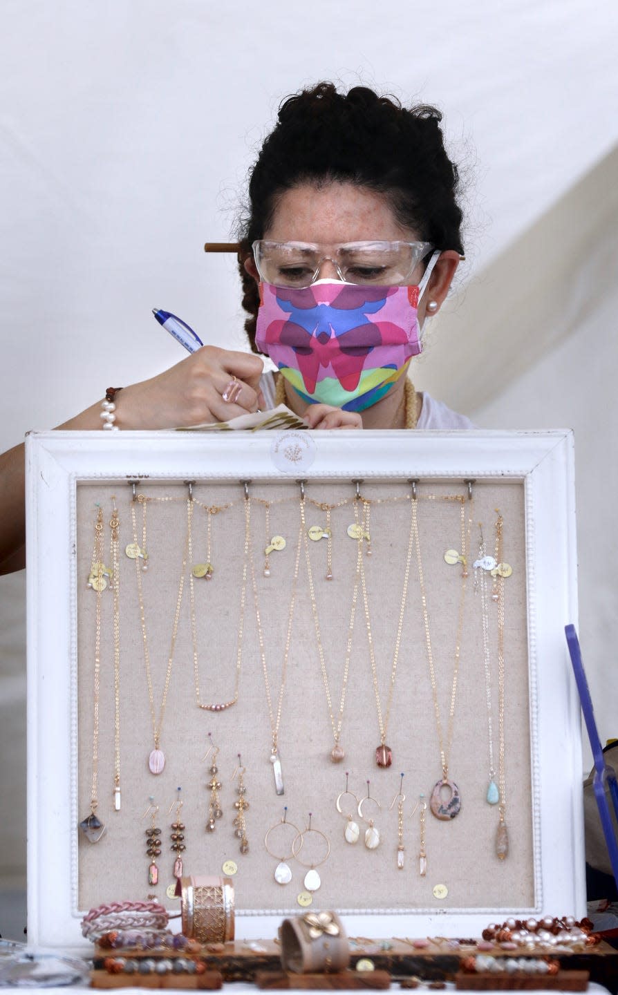 Jewelry maker Mildred Cortez of Bare Hand Creations finishes up with a customer's request at her tent at the Providence Flea on Sunday afternoon.