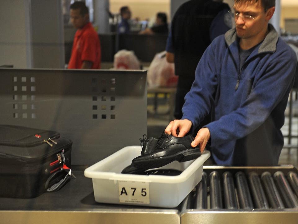 An air traveler places his shoes in a bin before passing through the TSA.