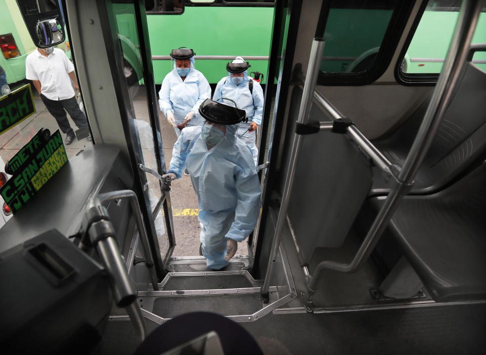 Members of cleaning crew wearing protective masks and suits disinfect a bus as a preventive measure against the spread of the new coronavirus, in Mexico City, Thursday, April 2, 2020. Mexico has started taking tougher measures against the new coronavirus, but some experts warn the country is acting too late and testing too little to prevent the type of crisis unfolding across the border in the United States. (AP Photo/Marco Ugarte)