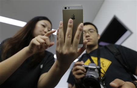 A staff member shows the new iPhone 5S Touch ID fingerprint recognition feature to a journalist at Apple Inc's announcement event in Beijing, September 11, 2013. REUTERS/Jason Lee
