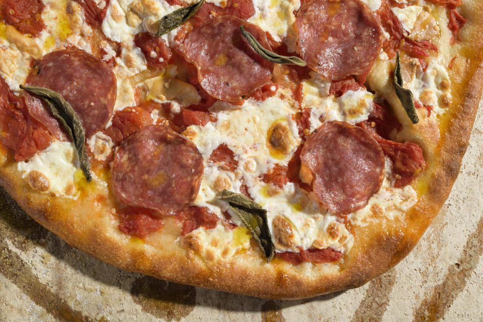 This image released by Milk Street shows a recipe for pizza with salami and smoked mozzarella. (Milk Street via AP)