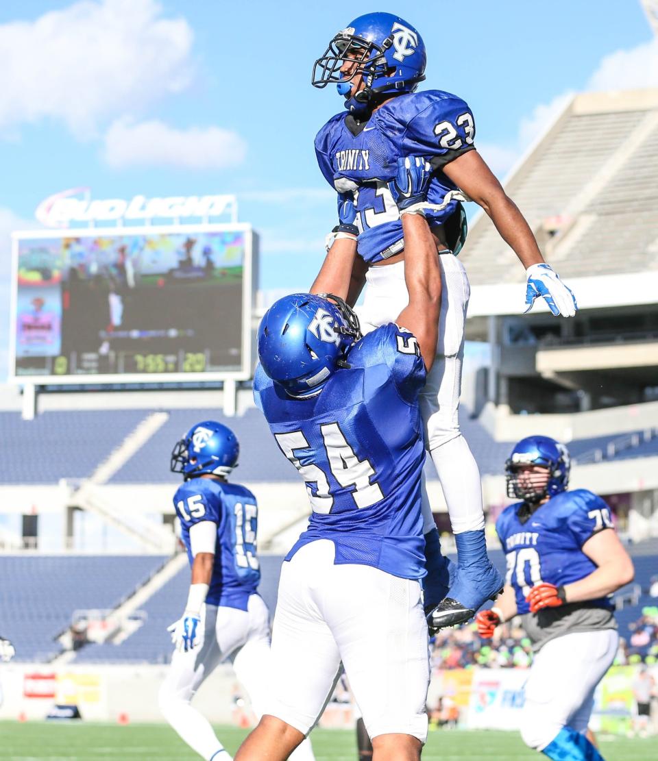 Trinity Christian's T.J. Jackson (54) hoists Rasheed Martin (23) after Martin scores their team's third touchdown against American Heritage during the second half of high school FHSAA Class 3A final football action at the Florida Citrus Bowl in Orlando, Fla., Saturday, December 6, 2014. [Gary McCullough/For the Times-Union]