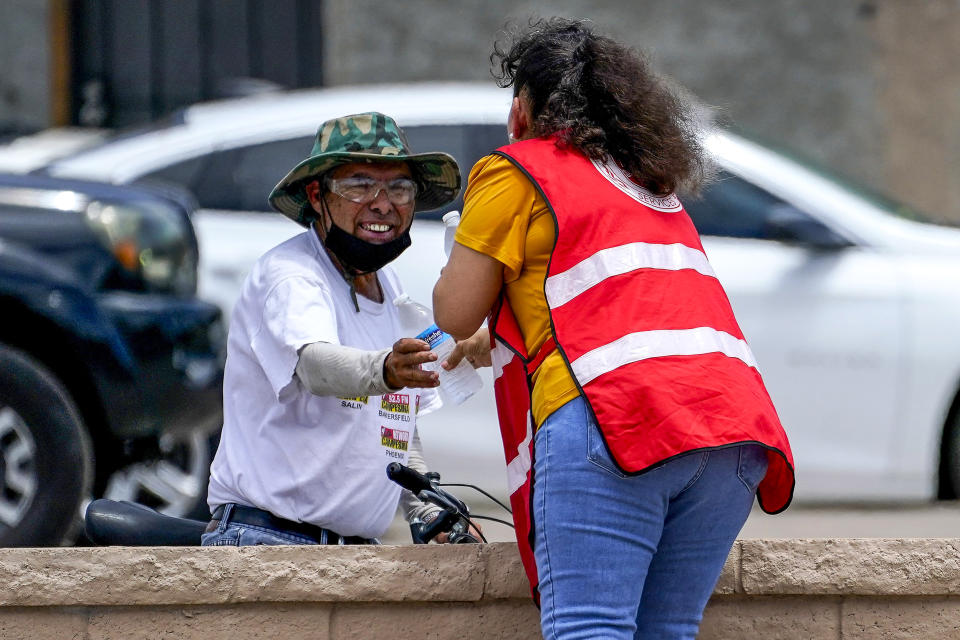 Image: Salvation Army volunteer Soila Arias gives water to a man at their Valley Heat Relief Station on July 11, 2023 in Phoenix.  (Matt York / AP)