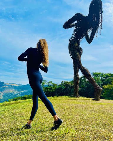 <p>Gisele Bundchen/Instagram</p> Gisele Bündchen mimics the pose of a towering sculpture during a visit to Brazil.