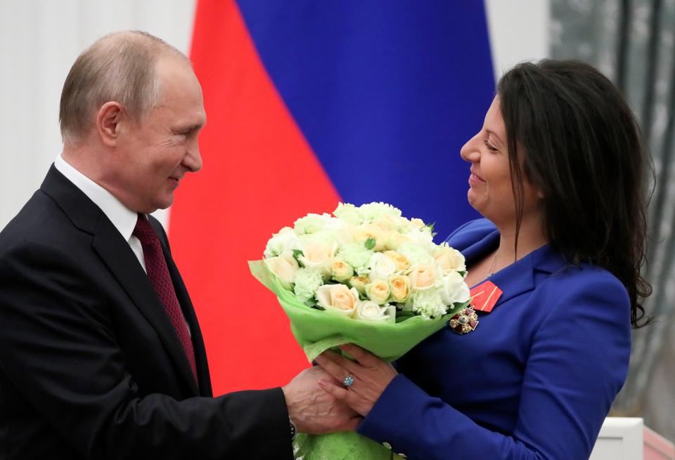 Putin, smiling, presents flowers to Margarita Simonyan, editor of the news network Russia Today.