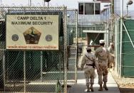 FILE - In this June 27, 2006 file photo, reviewed by a U.S. Department of Defense official, U.S. military guards walk within Camp Delta military-run prison, at the Guantanamo Bay U.S. Naval Base, Cuba. President Barack Obama is pushing to overcome obstacles to closing the Guantanamo Bay prison, an elusive goal which has frustrated him since he took office. That is setting the White House on a collision course with Congress in its bid to loosen restrictions for moving out detainees. (AP Photo/Brennan Linsley, File)