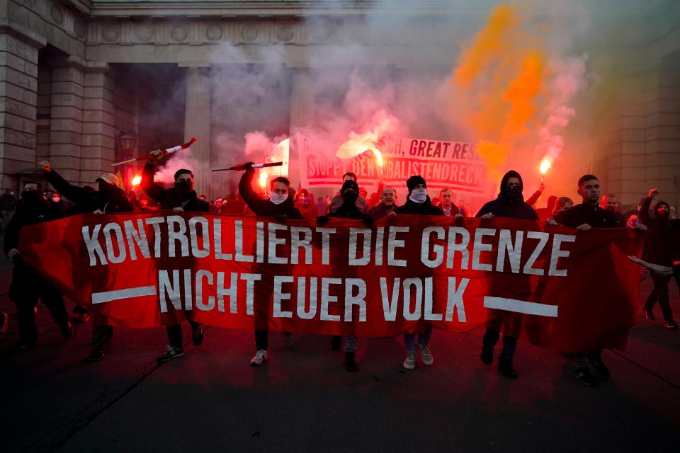 Demonstrators shout slogans and light flares during a demonstration against measures to battle the coronavirus pandemic in Vienna on Saturday. The banner reads: ‘ Control the border. Not your people’. (AP)