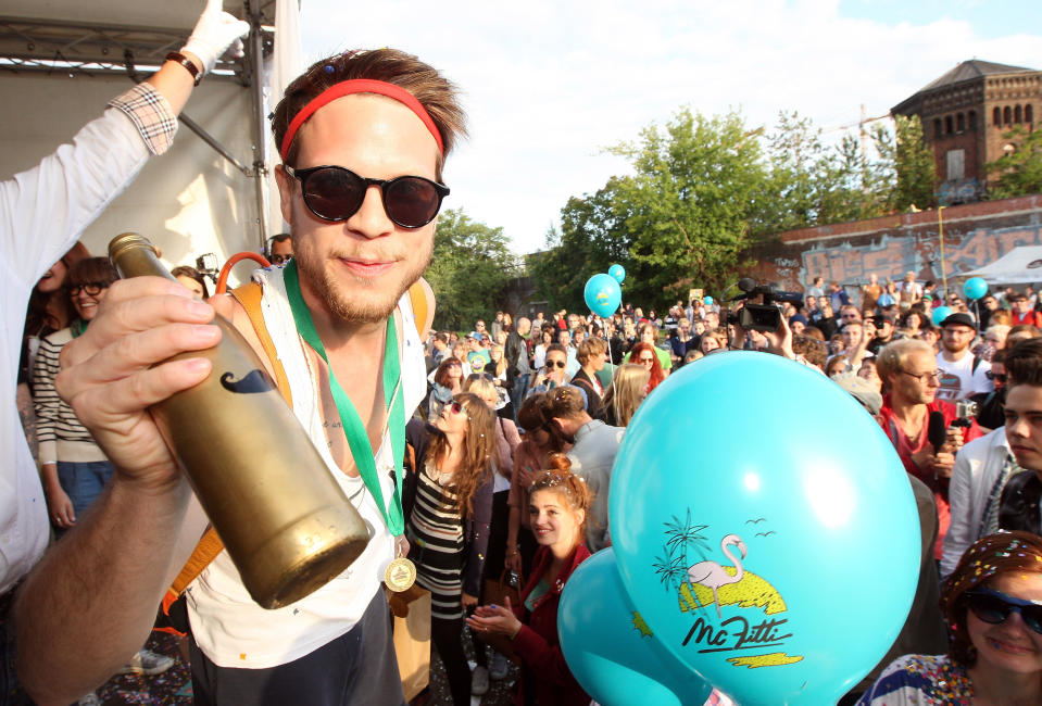 BERLIN, GERMANY - JULY 21: A member of the winning team, Jam FM, holds the "Golden Club Mate" trophe after winning the second annual Hipster Olympics on July 21, 2012 in Berlin, Germany. With events such as the "Horn-Rimmed Glasses Throw," "Skinny Jeans Tug-O-War," "Vinyl Record Spinning Contest" and "Cloth Tote Sack Race," the Hipster Olympics both mocks and celebrates the Hipster subculture, which some critics claim could never be accurately defined and others that it never existed in the first place. The imprecise nature of determining what makes one a member means that the symptomatic elements of adherants to the group vary in each country, but the archetype of the version in Berlin, one of the more popular locations for those following its lifestyle, along with London and Brooklyn, includes a penchant for canvas tote bags, the carbonated yerba mate drink Club Mate, analogue film cameras, asymmetrical haircuts, 80s neon fashion, and, allegedly, a heavy dose of irony. To some in Berlin, members of the hipster "movement" have replaced a former unwanted identity in gentrifying neighborhoods, the Yuppie, for targets of criticism, as landlords raise rents in the areas to which they relocate, particularly the up-and-coming neighborhood of Neukoelln. (Photo by Adam Berry/Getty Images)